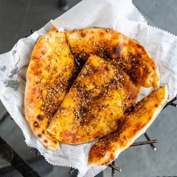 Za'atar bread, a Middle Eastern flatbread topped with herbs and sesame seeds, served in a basket.