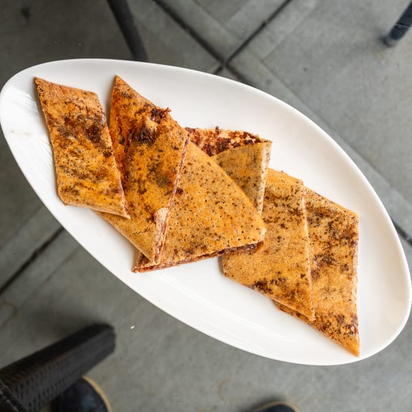 A white oval plate holds several triangular pieces of golden-brown dessert crepes with dark specks.
